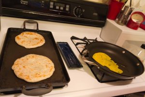 Heat up parathas and then start the first egg when they are almost done